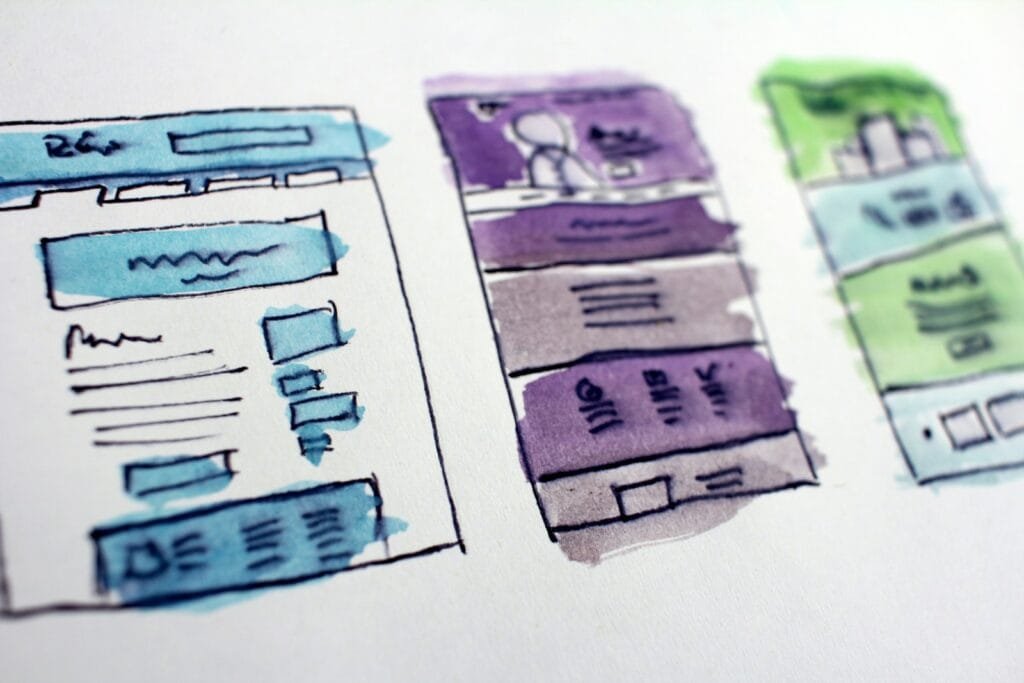 Bocetos de wireframes de una página web dibujados a mano sobre una mesa de trabajo de diseño