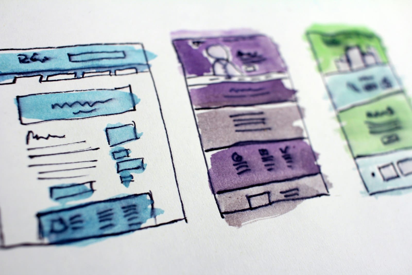 Bocetos de wireframes de una página web dibujados a mano sobre una mesa de trabajo de diseño